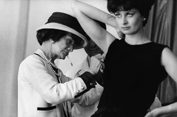 July or August 1961, Paris, France --- Fashion designer Coco Chanel adjusts the armhole of a model's dress with an assistant. --- Image by © Douglas Kirkland/CORBIS